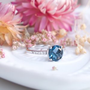 Bague pour femme en argent rhodié sertie d'une topaze blue london ronde etde diamants sur l'anneau