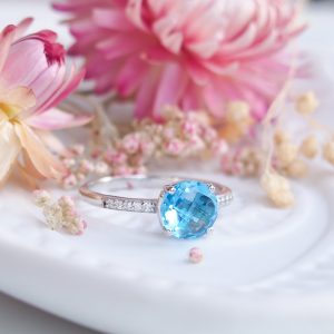 Bague pour femme en argent rhodié sertie d'une topaze swiss blue ronde et de diamants sur l'anneau