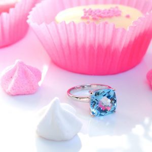 Bague Solitaire pour femme en argent rhodié sertie d'une topaze bleue coussin sur un anneau demi jonc